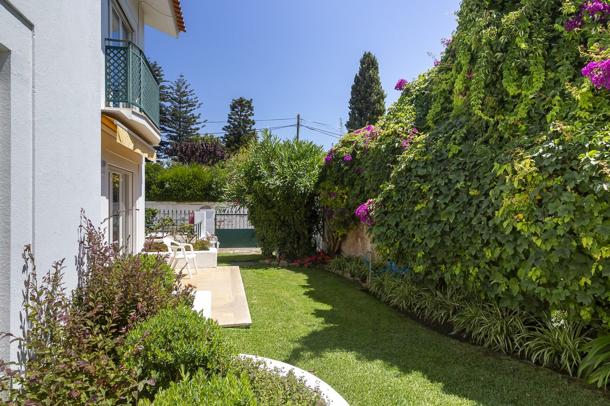 A side lawn with bougainvillea and a shaded patio beside the residence