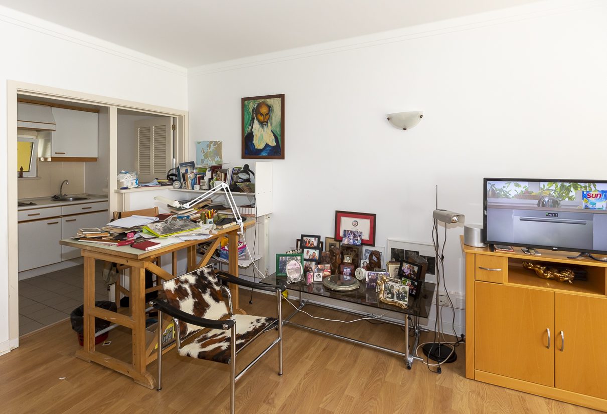 A resident's sitting room with a writing desk, kitchenette and personal photographs