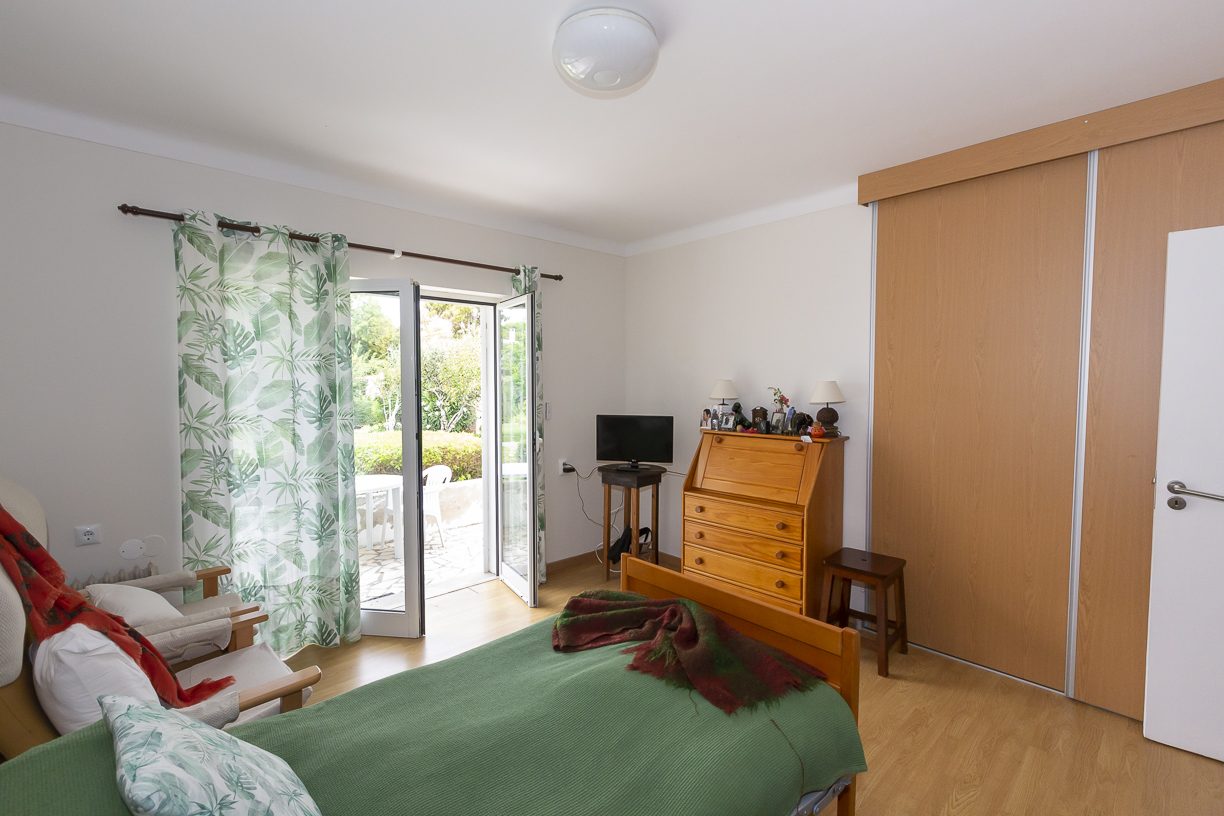 A light-filled bedroom with fitted wardrobes and doors to the garden